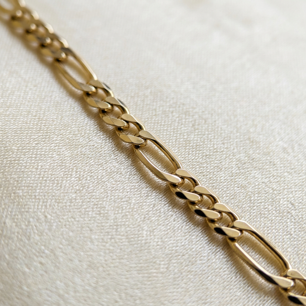 Close-up of polished yellow gold Figaro links on the G305 necklace