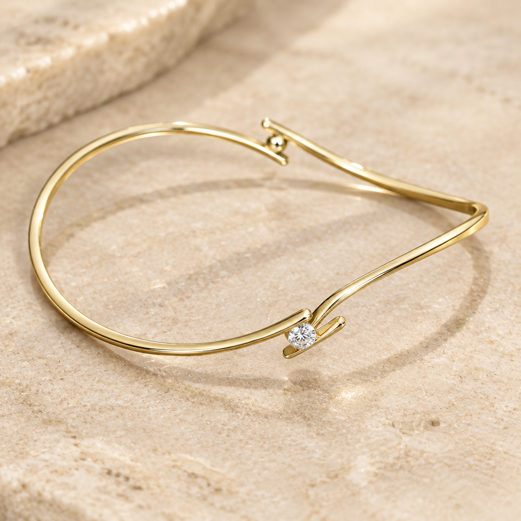Side view of a slender 14K yellow gold diamond bypass bangle