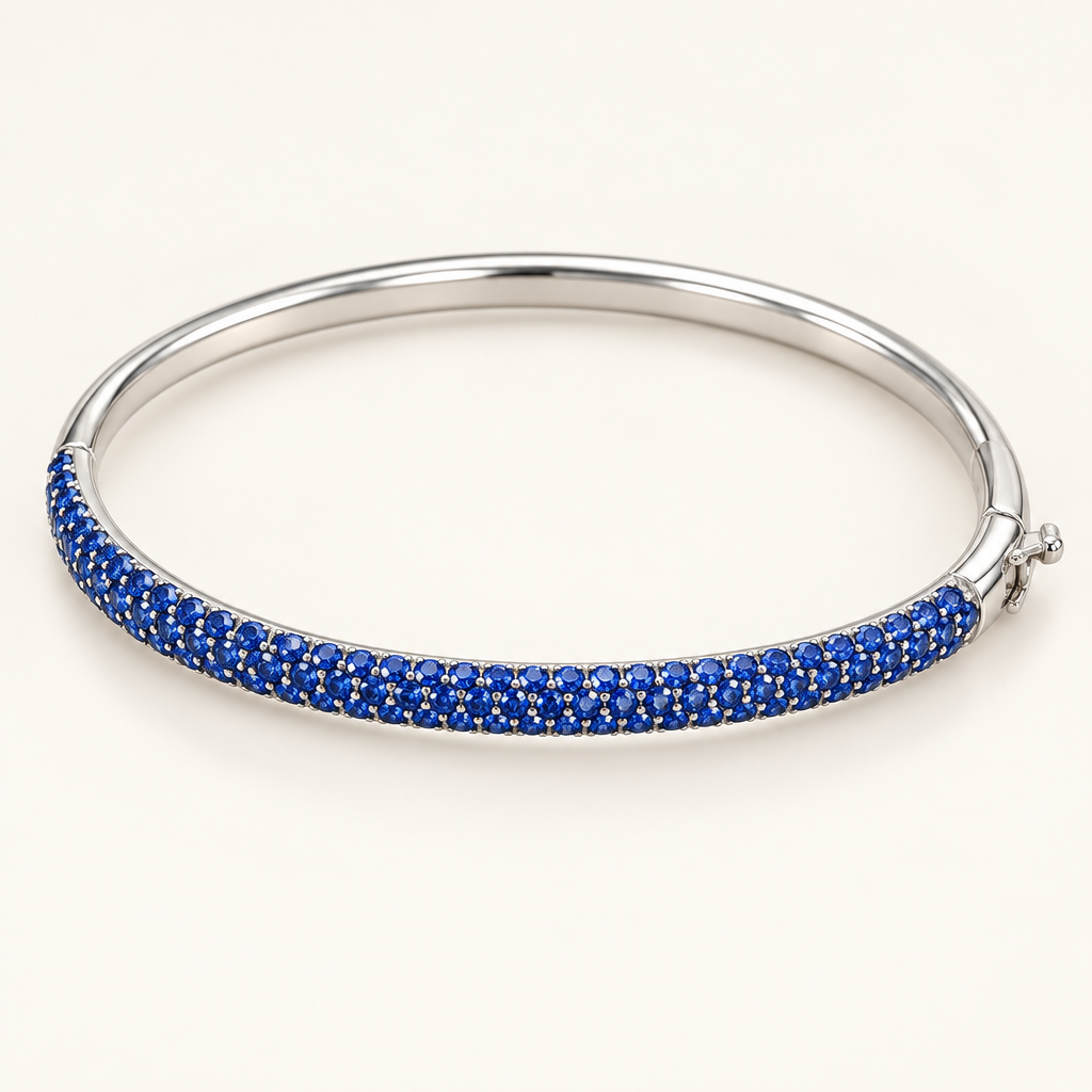 14K white gold bangle with rows of blue sapphires on an ivory background