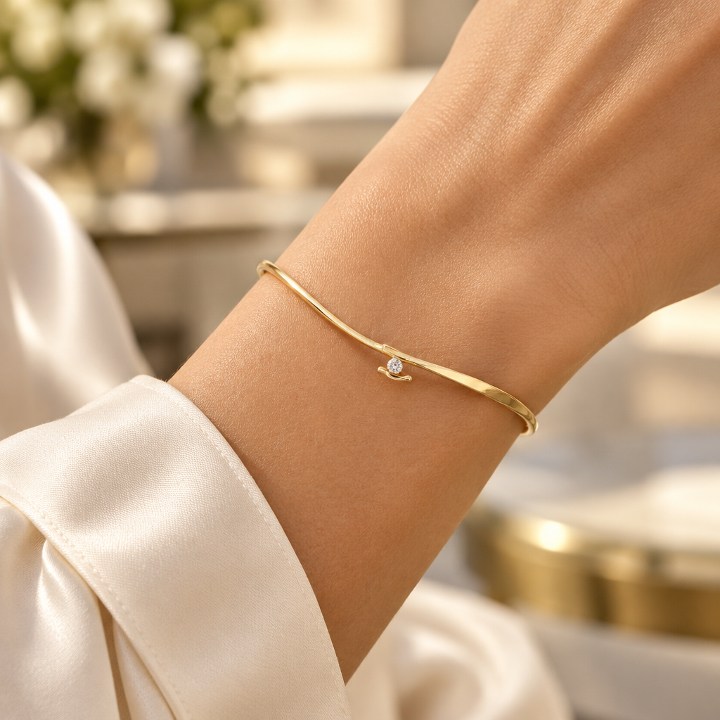 Woman wearing a delicate 14K yellow gold diamond bangle on her wrist