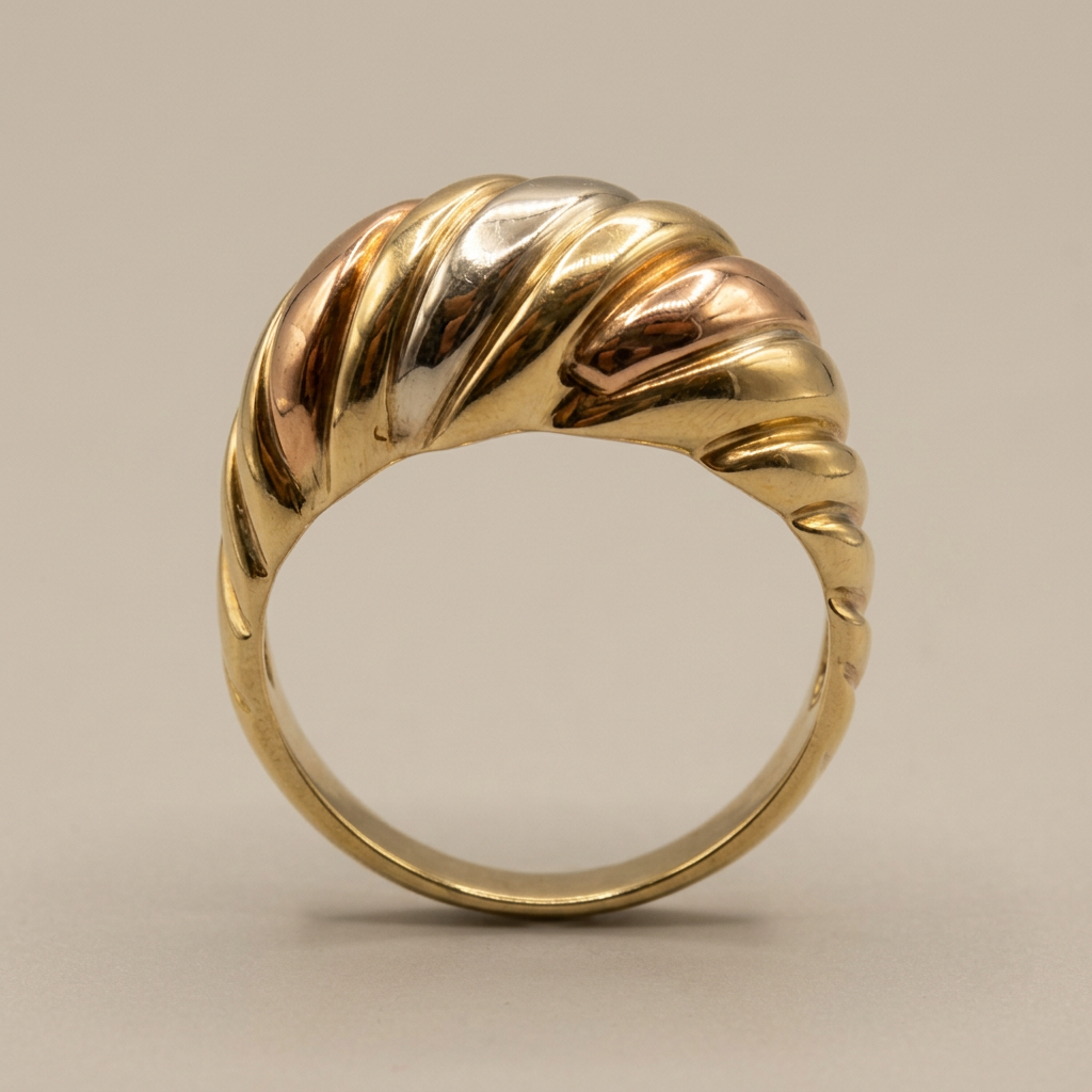 Side profile of the domed top and tapered band of a 10K tricolor gold ring