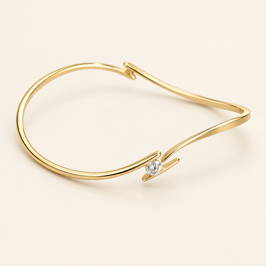 14K yellow gold bypass bangle with a single round diamond on an ivory background