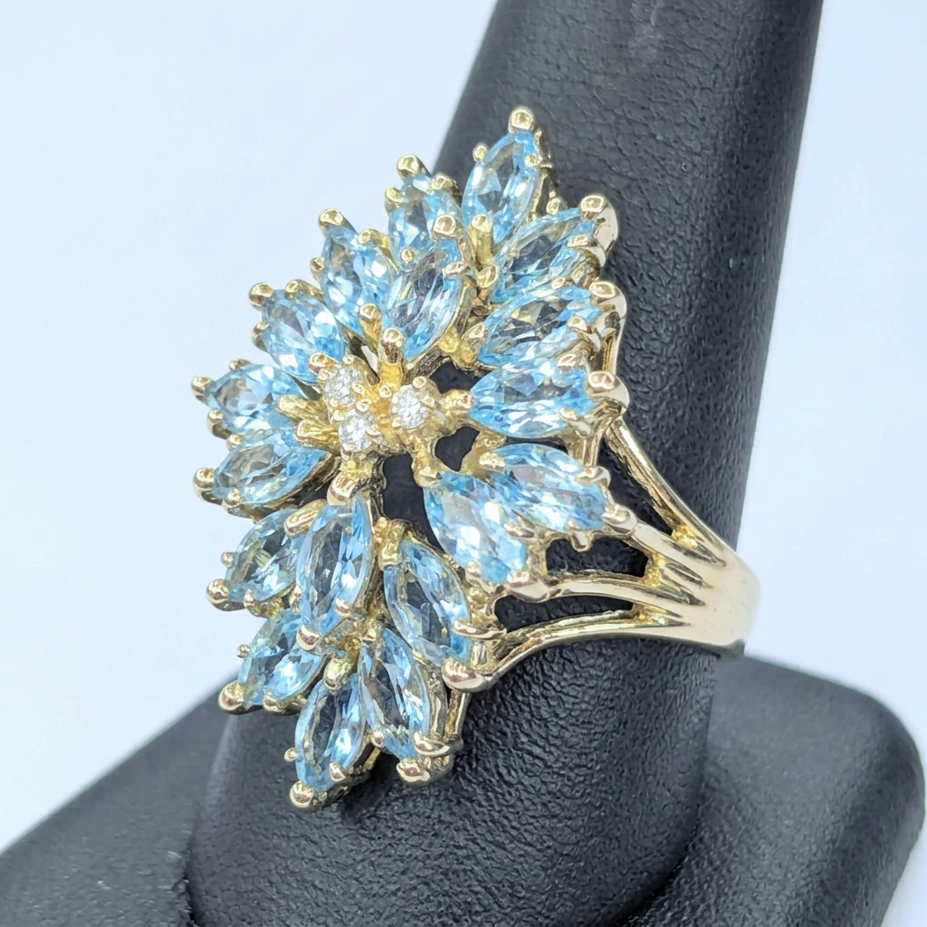 Angled view of the aquamarine and diamond cluster ring displayed on a dark stand