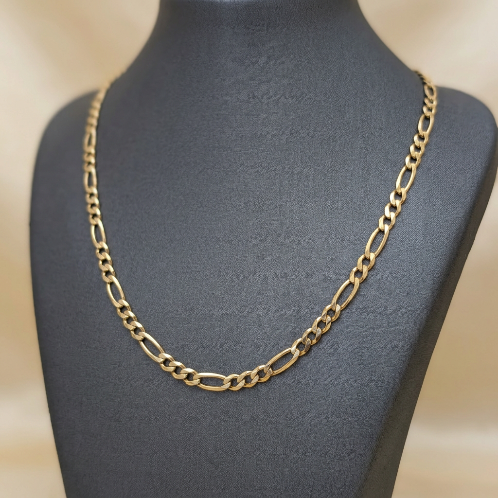 22-inch 10K yellow gold Figaro chain draped on a charcoal necklace bust