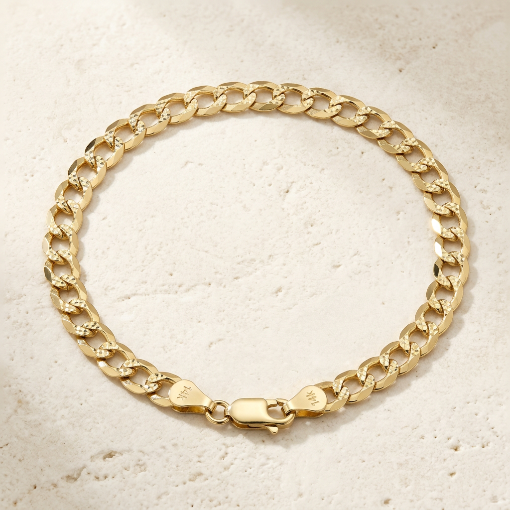 Yellow gold diamond-cut curb bracelet arranged on an ivory surface