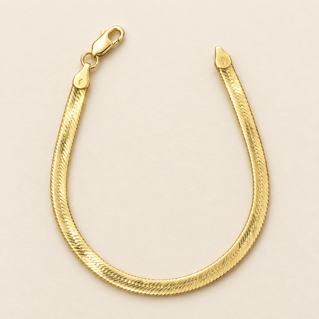 4.5mm yellow gold herringbone bracelet displayed open on ivory background