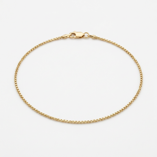 10K yellow gold round box link anklet arranged in an oval on white