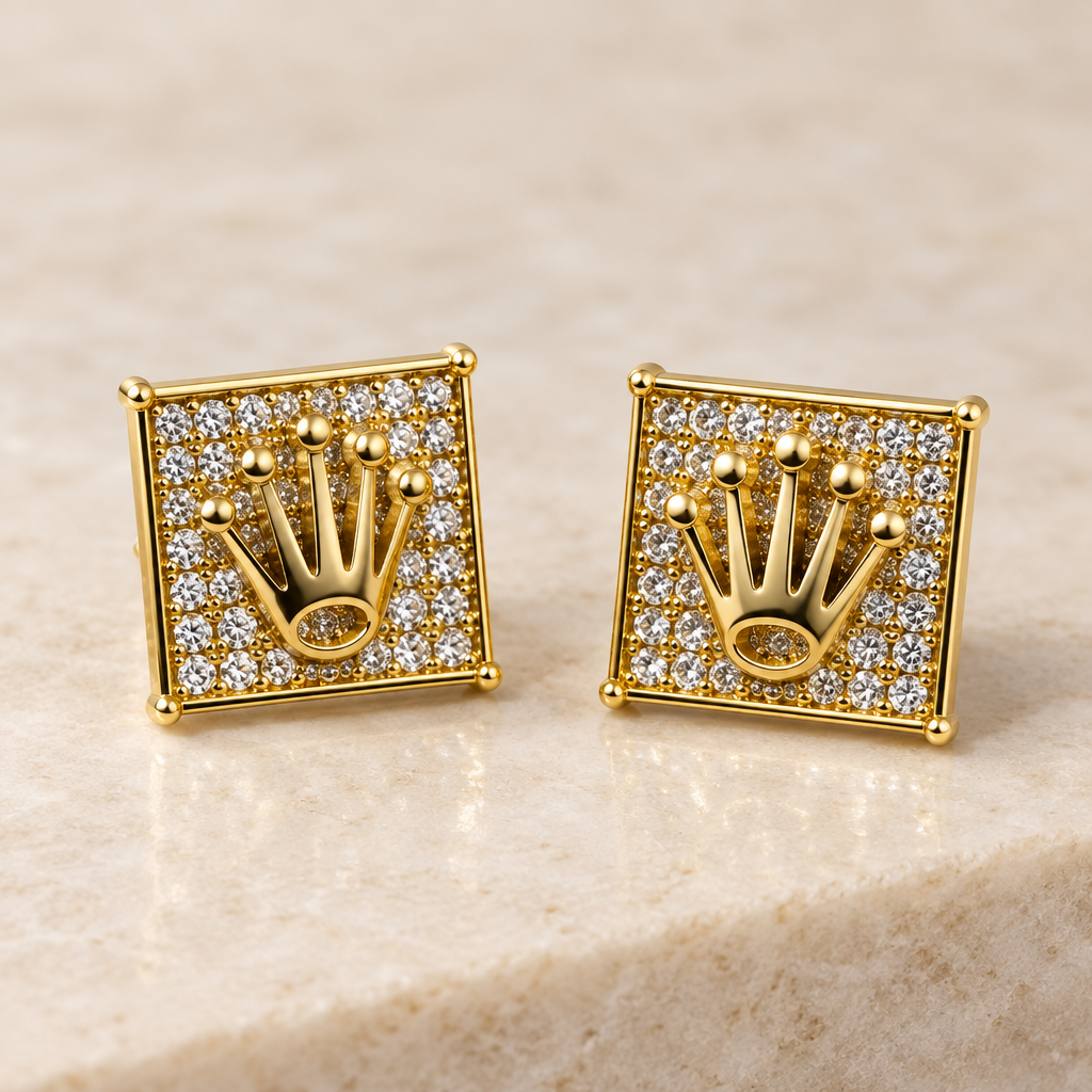 Angled view of yellow gold diamond crown stud earrings on an ivory surface