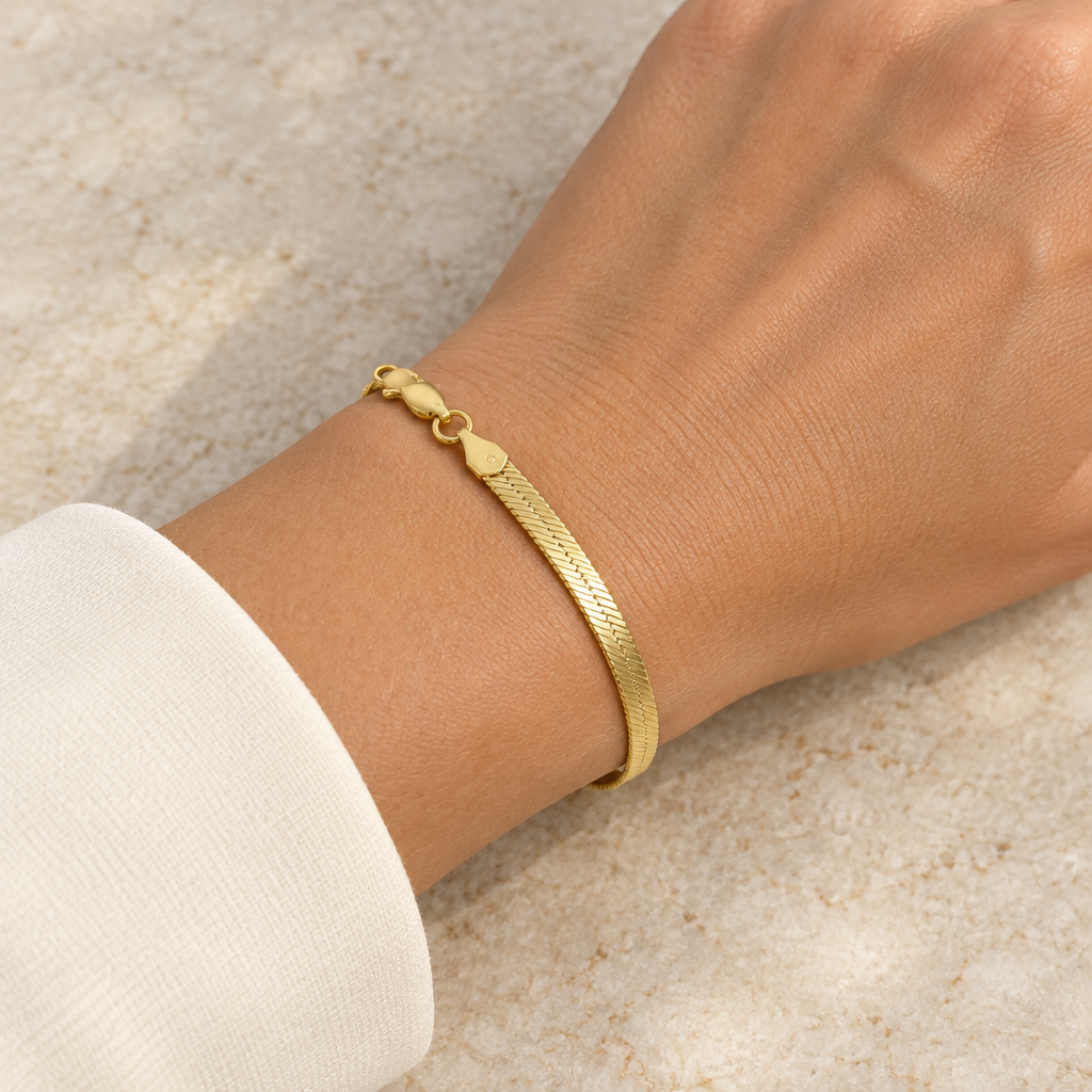 14K yellow gold herringbone bracelet worn on a wrist with ivory sleeve