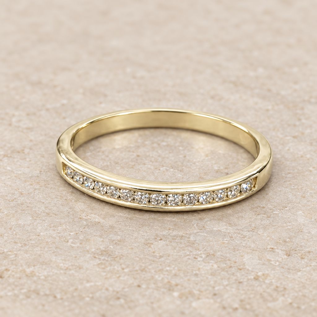 Angled view of the 2.6 gram yellow gold diamond band on a neutral stone surface